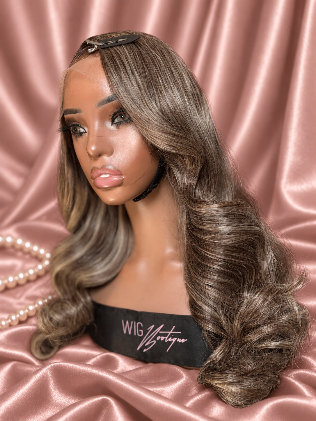 Amoura 18-inch highlighted wig, left-facing close view on rose-champagne satin with ivory pearls
